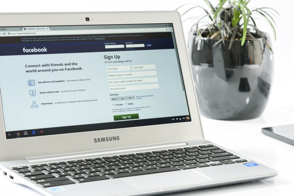 Laptop screen displaying Facebook sign up page with login fields and form on a white desk The Samsung laptop is angled with a plant in the background